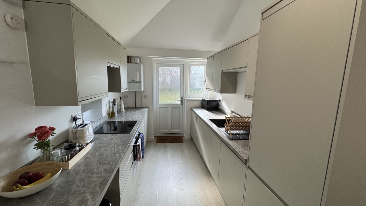 Fully equipped kitchen with induction cooker and dining area in Crawley apartment